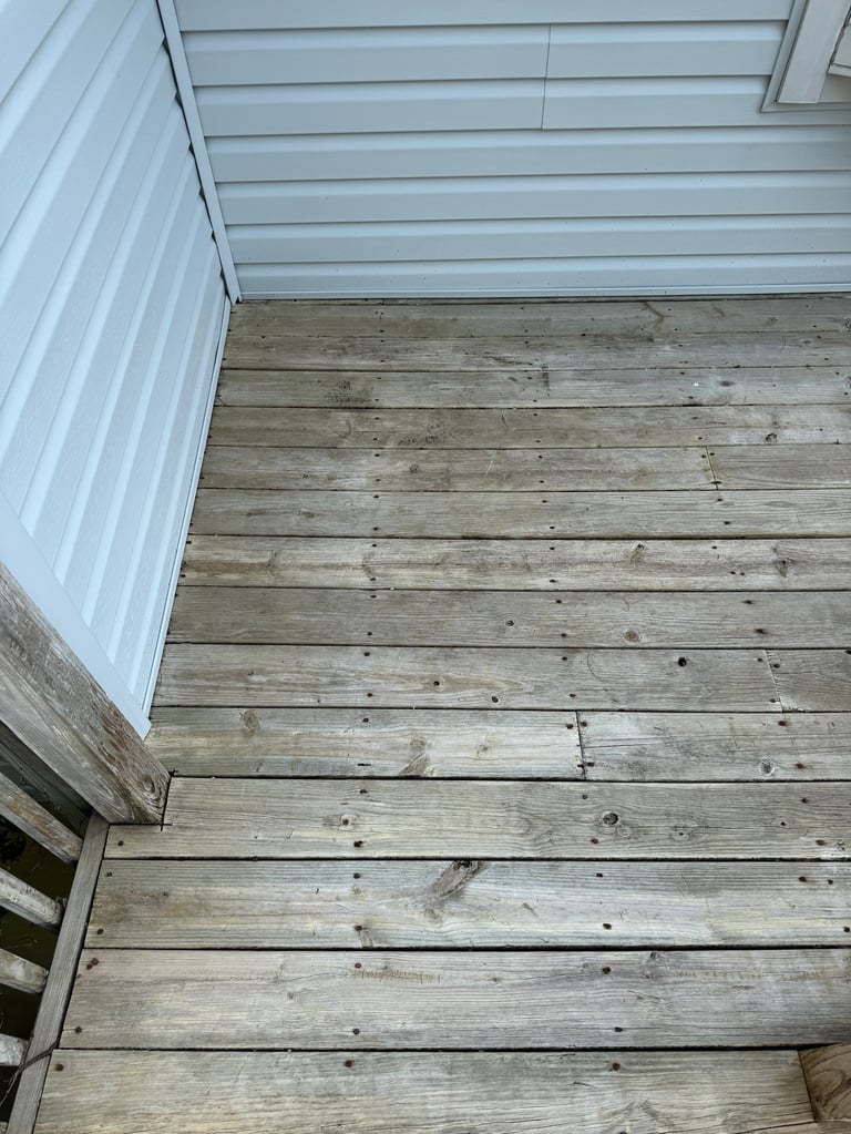 Wooden deck with horizontal planks next to white horizontal siding on a building exterior