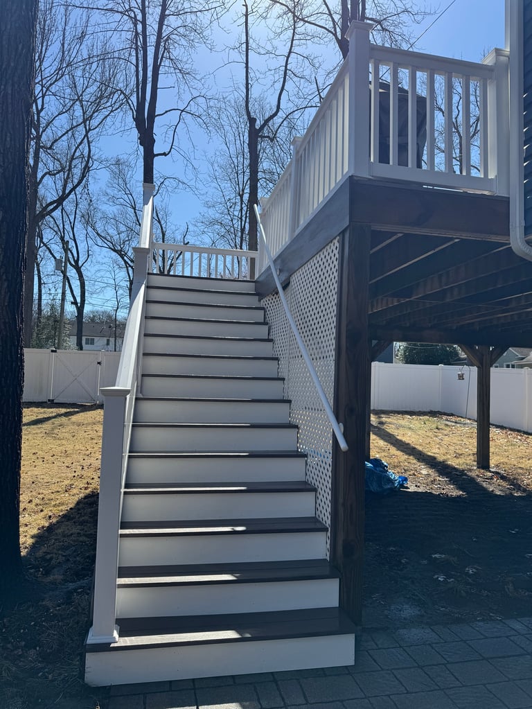 Gray metal staircase with railing leading to elevated deck on a residential property during daytime