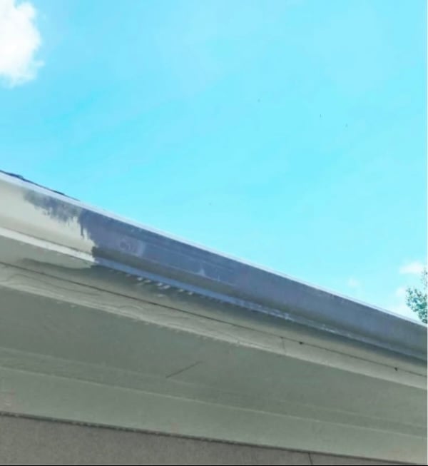 Solar panels mounted on a residential roof edge against a clear blue sky