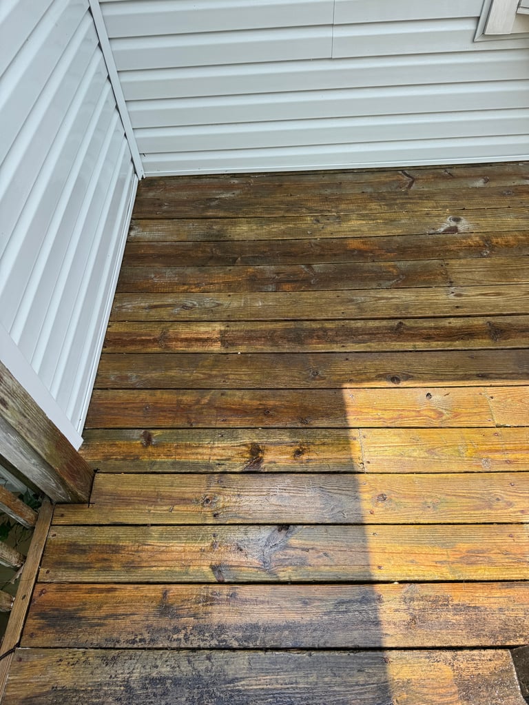 White metal siding overhang above weathered wooden deck planks with visible stains and wear patterns